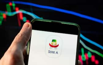 CHINA - 2021/12/09: In this photo illustration the Italian football professional top division Serie A logo seen displayed on a smartphone with an economic stock exchange index graph in the background. (Photo Illustration by Budrul Chukrut/SOPA Images/LightRocket via Getty Images)