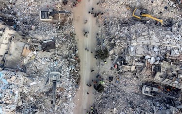 epa10460174 An aerial picture taken by drone shows excavators work on a collapsed building after a powerful earthquake in Hatay, Turkey, 11 February 2023. More than 24,000 people have died and thousands more are injured after two major earthquakes struck southern Turkey and northern Syria on 06 February. Authorities fear the death toll will keep climbing as rescuers look for survivors across the region.  EPA/ERDEM SAHIN