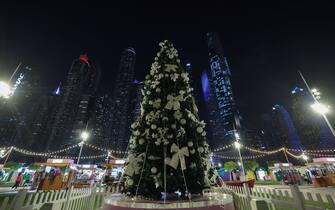 People take a stroll near a Christmas tree beneath the Dubai skyline on December 15, 2023. (Photo by Giuseppe CACACE / AFP) (Photo by GIUSEPPE CACACE/AFP via Getty Images)