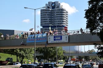 epa10839456 Activists of Extinction Rebellion hang down from a bridge close to the BMW headquarters to protest against the International Motor Show (IAA) in Munich, Germany, 04 September 2023. The 2023 International Motor Show Germany IAA MOBILITY 2023 takes place in Munich from 05 to 10 September 2023. IAA 2023 will also feature numerous world premieres, and has a special focus on electric mobility and digitization.  EPA/ANNA SZILAGYI