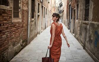 A young woman walks down an old street in Italy