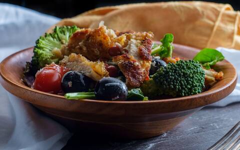 Vegetable salad with breaded crispy chicken cutlets broccoli grape tomatoes and romaine lettuce