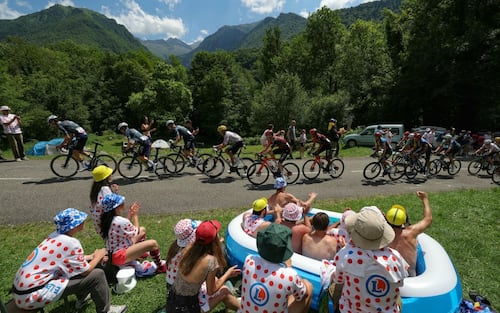 TOPSHOT - Spectators in an inflatable pool cheers as the pack of riders (peloton) cycles past during the 15th stage of the 111th edition of the Tour de France cycling race, 197,7 km between Loudenvielle and Plateau de Beille, in the Pyrenees mountains, southwestern France, on July 14, 2024. (Photo by Thomas SAMSON / AFP) (Photo by THOMAS SAMSON/AFP via Getty Images)