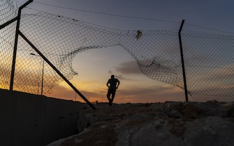 Refugee man running behind fence,