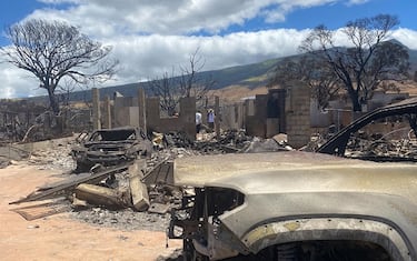 Residents walk among their destroyed home in the aftermath of a wildfire in Lahaina, western Maui, Hawaii on August 11, 2023. A wildfire that left Lahaina in charred ruins has killed at least 55 people, authorities said on August 10, making it one of the deadliest disasters in the US state's history. Brushfires on Maui, fueled by high winds from Hurricane Dora passing to the south of Hawaii, broke out August 8 and rapidly engulfed Lahaina. (Photo by Paula RAMON / AFP) / "The erroneous mention[s] appearing in the metadata of this photo by Paula RAMON has been modified in AFP systems in the following manner: [August 11] instead of [August 10]. Please immediately remove the erroneous mention[s] from all your online services and delete it (them) from your servers. If you have been authorized by AFP to distribute it (them) to third parties, please ensure that the same actions are carried out by them. Failure to promptly comply with these instructions will entail liability on your part for any continued or post notification usage. Therefore we thank you very much for all your attention and prompt action. We are sorry for the inconvenience this notification may cause and remain at your disposal for any further information you may require." (Photo by PAULA RAMON/AFP via Getty Images)