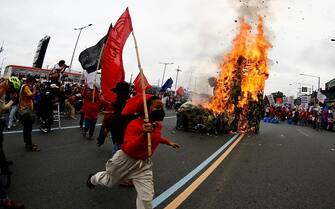 epaselect epa10765348 Activists burn an effigy during a protest rally along a road leading to the Congress compound in Quezon city, Metro Manila, Philippines, 24 July 2023. The protesters gathered against the State of the Nation Address (SONA) of President Ferdinand 'Bongbong' Marcos.  EPA/FRANCIS R. MALASIG