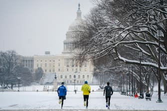 epa11082935 Joggers run on the National Mall near the US Capitol following the first snowfall of the year in Washington, DC, USA, 16 January 2024. Two to six inches of snow, the most in two years, is blanketing the DC region with light snow showers and freezing rain forecast through the morning.  EPA/SHAWN THEW