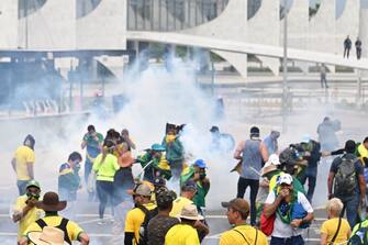 Supporters of Brazilian former President Jair Bolsonaro clash with the police during a demonstration outside the Planalto Palace in Brasilia on January 8, 2023. - Brazilian police used tear gas Sunday to repel hundreds of supporters of far-right ex-president Jair Bolsonaro after they stormed onto Congress grounds one week after President Luis Inacio Lula da Silva's inauguration, an AFP photographer witnessed. (Photo by EVARISTO SA / AFP) (Photo by EVARISTO SA/AFP via Getty Images)