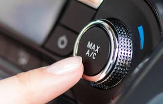 Air conditioner control panel, car cooling system. Finger presses the AC knob