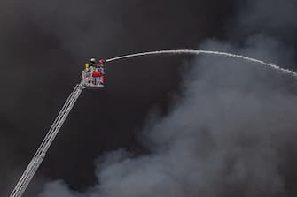 epa10566212 Firefighters try to extinguish a fire burning at a warehouse in the Rothenburgsort district of Hamburg, Germany, 09 April 2023. Residents have been warned of heavy smoke and possible toxins in the air. An alert issued by the Hamburg fire department said smoke gasses and chemical components in the air could affect breathing.  EPA/DOMINICK WALDECK