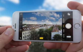 Hands holding Iphone 6, using camera app to take a HDR picture of a city skyline.