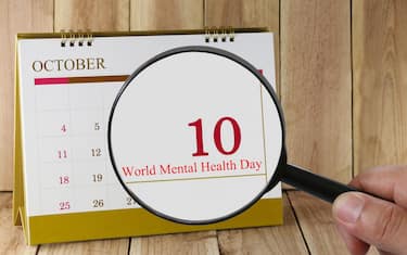 Magnifying glass in hand on calendar you can look World Mental Health Day in 10 October,concept of a public relations campaign M