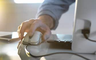 Businessman's hand on a computer mouse working in office