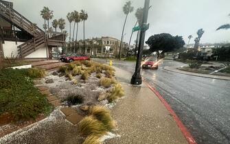 A vehicle drives down a road as hail and rain fall during a winter storm that blanketed the region in Redondo Beach, California, on February 25, 2023. - Heavy snow fell in southern California as the first blizzard in a generation pounded the hills around Los Angeles, with heavy rains threatening flooding in other places. (Photo by Patrick T. Fallon / AFP) (Photo by PATRICK T. FALLON/AFP via Getty Images)