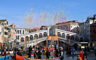 Revellers parade on boats sailing on the Grand Canal in front of Rialto bridge during Venice Carnival, on February 16, 2025. This year, the theme of one of the most famous carnival in the world is Casanova, as the 'Serenissima' celebrates the 300th anniversary of the famous man's birth. (Photo by ANDREA PATTARO / AFP)