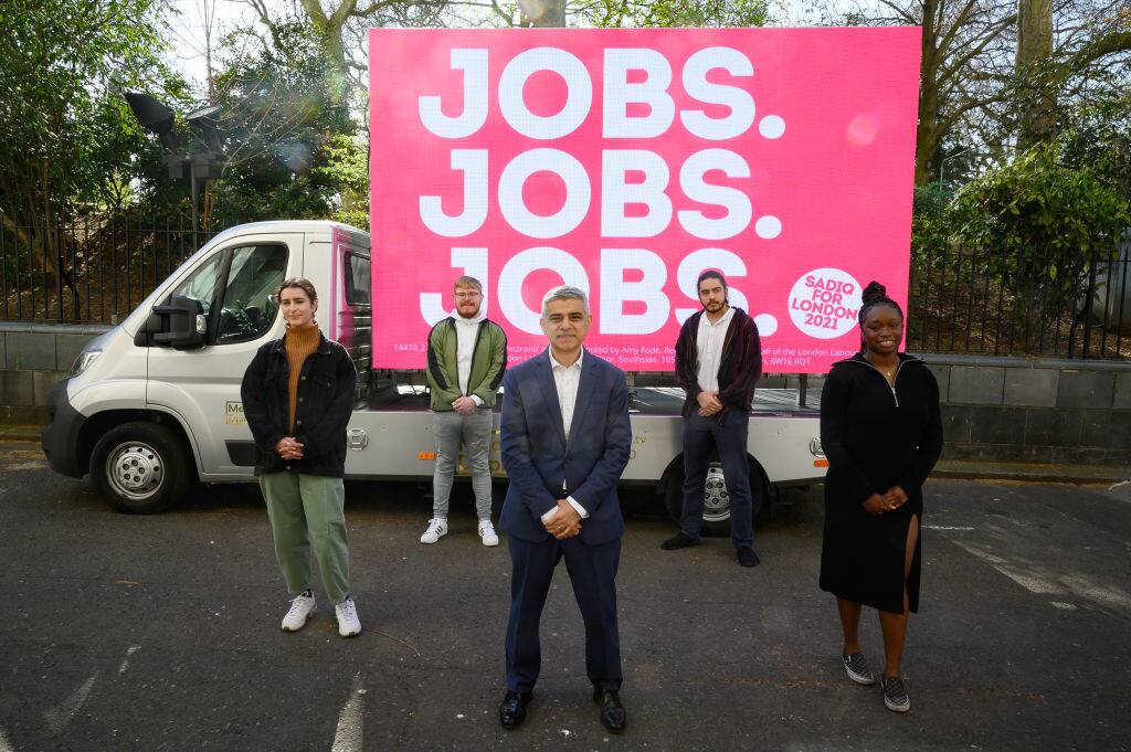 LONDON, ENGLAND - MARCH 30: Mayor of London Sadiq Khan poses for photographers in front of a poster stating his Mayoral campaign pledge of "Jobs Jobs Jobs" on March 30, 2021 in London, England. Candidates for the London Mayoral election include incumbent Sadiq Khan for the Labour Party, Shaun Bailey - Conservative, Kam Balayev - Renew, Sian Berry - Green Party, Laurence Fox - Reclaim Party, Peter Gammons - UKIP, Luisa Porritt - Liberal Democrats and Mandu Reid - Women's Equality Party alongside a number of Independents. Londoners will go to the polls on Thursday, May 6, 2021. (Photo by Leon Neal/Getty Images)