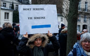 A woman holds a placard which reads as "Serene death, serene life" during a pro-euthanasia demonstration near the National Assembly in Paris on January 23, 2024. The inclusion of abortion in the Constitution, promised by Emmanuel Macron, is due to be debated in the National Assembly on 24 January before being examined in the Senate, where the right-wing majority has never hidden its scepticism, with a view to possible adoption by Congress in early March. On January 21, opponents of abortion took advantage of their traditional "March for Life" in Paris to denounce this constitutional reform bill as well as the future law on the end of life. (Photo by Dimitar DILKOFF / AFP) (Photo by DIMITAR DILKOFF/AFP via Getty Images)