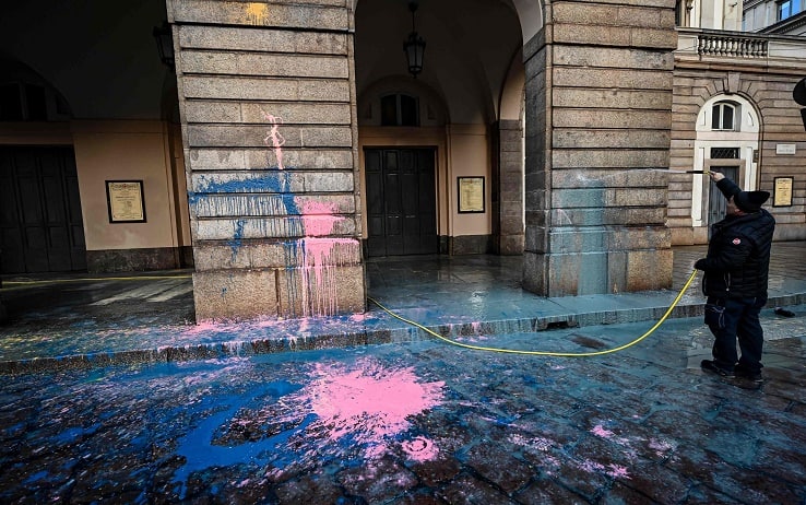 An employee hoses the facade of the La Scala theater in Milan on December 7, 2022 after environmental activists from the "Last Generation" (Ultima Generazione) group smeared it with paint during a group's action aimed at raising awareness about climate change on the day of La Scala's new season's opening. (Photo by Piero CRUCIATTI / AFP)