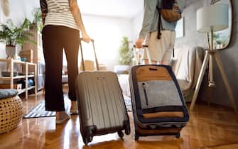 Rear-view of an unrecognizable couple arriving at the accommodation with their suitcases