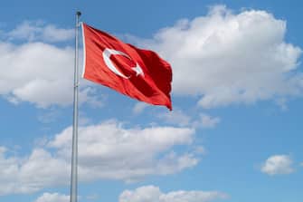 Flag of Turkey on blue sky wind background.