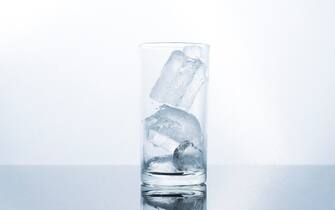 glass water with ice water in glass on wet plate and white background  drink and party concept