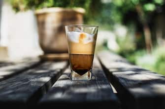 Ice coffe with milk and ice cubes on top, lying on a wooden table, to start a day with a good breakfast