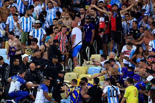 RIO DE JANEIRO, BRAZIL - NOVEMBER 21: Police officers armed with batons clash with fans as the match is delayed due to the incidents prior to a FIFA World Cup 2026 Qualifier match between Brazil and Argentina at Maracana Stadium on November 21, 2023 in Rio de Janeiro, Brazil. (Photo by Buda Mendes/Getty Images)