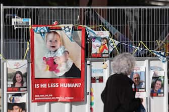 epa11087295 People walk past a picture of Israeli toddler Kfir Bibas who is held hostage by Hamas in Gaza as people attend to celebrate baby's birthday, outside the Kirya military base in Tel Aviv, Israel, 18 January 2024. Attendees were also calling for the immediate release of all hostages. The Bibas family, mother Shiri Bibas, her husband Yarden Bibas along with their children Kfir who turned one and four-year-old boy Ariel, were kidnapped by Hams from their home in Kibbutz Nir Oz during the attack on 07 October 2023. According to the Israeli army, 133 Israelis are still held hostage by Hamas in Gaza.  EPA/ABIR SULTAN