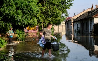 epaselect epa10676352 A boy carries his belongings as he evacuates from his home in a flooded street of Kherson, Ukraine, 06 June 2023.  Ukraine has accused Russian forces of destroying a critical dam and hydroelectric power plant on the Dnipro River in the Kherson region along the front line in southern Ukraine on 06 June. A number of settlements were completely or partially flooded, Kherson region governor Oleksandr Prokudin said on telegram. Russian troops entered Ukraine on 24 February 2022 starting a conflict that has provoked destruction and a humanitarian crisis.  EPA/IVAN ANTYPENKO