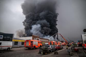 epa10566216 Firefighters try to extinguish a fire burning at a warehouse in the Rothenburgsort district of Hamburg, Germany, 09 April 2023. Residents have been warned of heavy smoke and possible toxins in the air. An alert issued by the Hamburg fire department said smoke gasses and chemical components in the air could affect breathing.  EPA/DOMINICK WALDECK