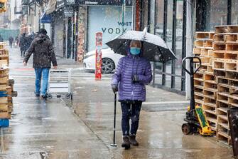 epa11090540 People walk on Bowery as snow falls in New York, New York, USA, 19 January 2024.  EPA/SARAH YENESEL
