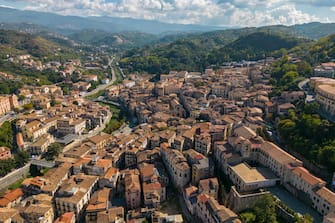 This photo is taken by a drone. It shows the old city center of Cosenza, the capital of the province Calabria in Italy. You can see the old typical Italian houses in the hills with a sunny but cloudy sky.
