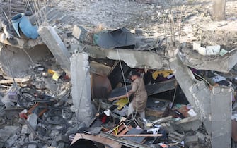 A man salvages objects amid rubble of a school hit during an Israeli strike before the start of a four-day truce in the battles between Israel and Hamas militants, in Rafah in the southern Gaza Strip on November 24, 2023. A four-day truce in the Israel-Hamas war began on November 24, with hostages set to be released in exchange for prisoners in the first major reprieve in seven weeks of war that have claimed thousands of lives. (Photo by Mohammed ABED / AFP) (Photo by MOHAMMED ABED/AFP via Getty Images)