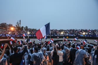 Athletes from France's delegation cheer on to spectators on a bridge as they sail in a boat along the river Seine during the opening ceremony of the Paris 2024 Olympic Games in Paris on July 26, 2024. (Photo by Franck FIFE / POOL / AFP) (Photo by FRANCK FIFE/POOL/AFP via Getty Images)