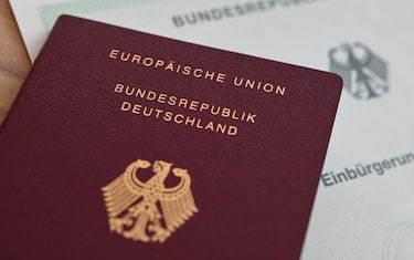 ILLUSTRATION - 24 June 2024, Baden-Württemberg, Stuttgart: A German passport and a naturalization certificate lie on a table. Photo: Marijan Murat/dpa (Photo by Marijan Murat/picture alliance via Getty Images)