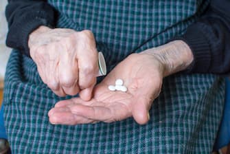 Hands of very old woman taking pills