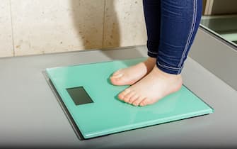 Child's foot is standing on modern floor scale measuring her weight.