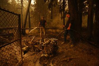 Curt Derkson sprays water on hot spots near a house in Celista, British Columbia, Canada, on Saturday, Aug. 19, 2023. Record-breaking wildfires in Canada, which have already scorched an area larger than Greece, are heading toward key population centers, forcing tens of thousands to evacuate. Photographer: Cole Burston/Bloomberg via Getty Images