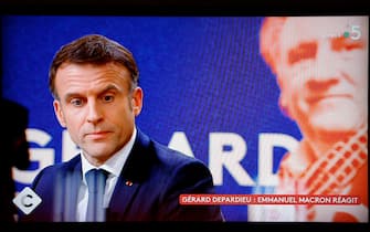 This photograph taken on December 20, 2023 shows a television screen broadcasting French TV channel France 5 as French President Emmanuel Macron speaks during an interview in the "C a vous" TV show, at the Elysee Presidential Palace, in Paris, following the approval of the law to control immigration, on the eve. French President Emmanuel Macron said on December 20, 2023 French film icon Gerard Depardieu, accused of rape, had become the target of a "manhunt" as the actor faces fresh scrutiny over sexist comments. (Photo by Ludovic MARIN / AFP) (Photo by LUDOVIC MARIN/AFP via Getty Images)