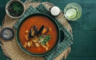 Traditional fisherman's stew from Tuscany. Made with octopus, squid, mussels, clams and fish. Flat lay top-down composition on dark green background.