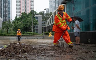 Workers clean up on a muddy road in Hong Kong on September 8, 2023, following major flooding. Record rainfall in Hong Kong caused widespread flooding in the early hours on September 8, disrupting road and rail traffic just days after the city dodged major damage from a super typhoon. (Photo by Bertha WANG / AFP) (Photo by BERTHA WANG/AFP via Getty Images)