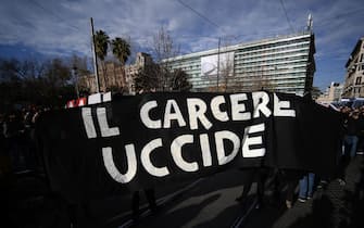 Members of anarchists groups hold a banner reading "Prison Kills" as they stage an unauthorised protest on February 4, 2023 in Rome, in support of anarchist Alfredo Cospito, incarcerated  under the "41-bis" highly restrictive detention regime. - The failing health of an incarcerated anarchist has rekindled debate in Italy over hard prison time usually reserved for mafia bosses, with the new right-wing government vowing not to cave in. Around 730 people behind bars in Italy are subject to the country's highly restrictive detention regime known as "41-bis", among them anarchist Alfredo Cospito, 55. (Photo by Filippo MONTEFORTE / AFP) (Photo by FILIPPO MONTEFORTE/AFP via Getty Images)