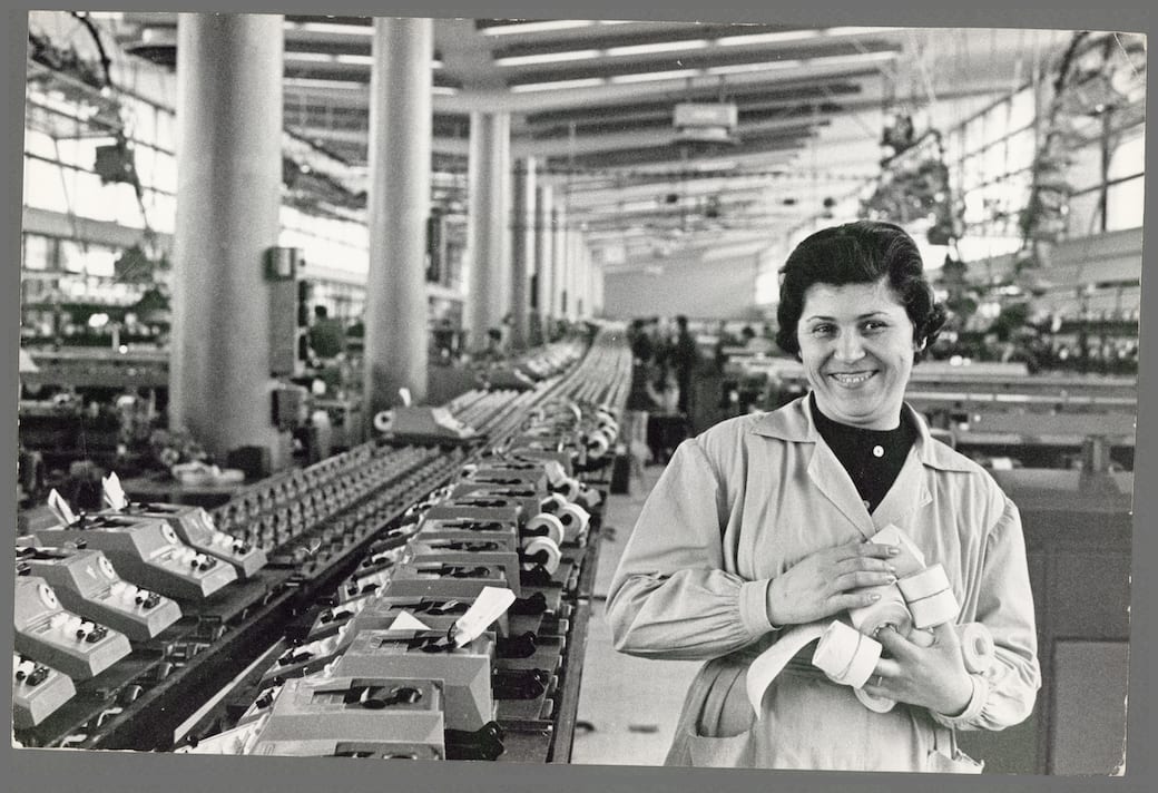 Operaia sorridente tiene in mano dei rotoli di carta nella fabbrica di macchine da scrivere Olivetti, Pozzuoli, 1960-1970. Foto Giancarlo Scalfati. Fondazione Gramsci. Crediti fotografici: Foto Giancarlo Scalfati. Archivio Fondazione Gramsci