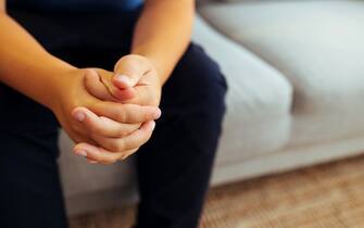 Boy sitting on sofa with folded hands