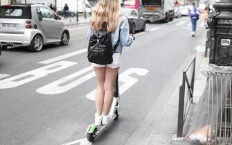 epa07647960 A girl rides a Dock-free electric scooters as another lies on the pavement, in Paris, France, 14 June 2019. Dockless electric scooter companies have been emerging quickly, with more and more devices adorning the streets of Paris - becoming a fast growing headache for Paris authorities trying to implement safety regulations. Earlier in June, Paris saw its first fatality after a man riding a scooter was killed in a traffic collision in the city center. Fines have already been implemented for riding scooters on the sidewalks, and Paris mayor Anne Hidalgo announced a ban on parking scooters on the pavement.  EPA/IAN LANGSDON