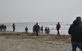 Personale del 118 e della Croce rossa presta soccorso ai superstiti del peschereccio che si è spezzato in due, a "Steccato" di Cutro, nel Crotonese, 26 febbraio 2023. I circa cinquanta superstiti trovati sulla spiaggia hanno raccontato ai soccorritori, infatti, che sul peschereccio su cui viaggiavano, che si è spezzato in due a causa del mare molto mosso, erano almeno in 250. ANSA/GIUSEPPE PIPITA