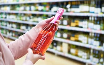 Bottle of rose wine in the hands of the buyer in the store