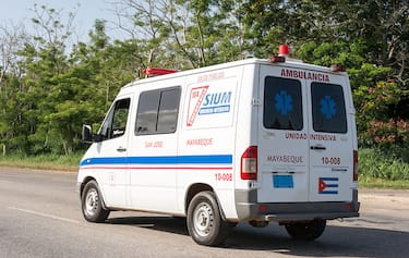 HIGHWAY, HAVANA, CUBA - 2014/07/04: Everyday Cuban scenes: White ambulance part of the health care system drives down the Autopista Nacional.

The ambulance has blue and red striped on the side, and blue caduceus symbols on the back windows. The Spanish words "ambulancia", "unidad intensivia", and "Mayabeque" are written in red on the back. (Photo by Roberto Machado Noa/LightRocket via Getty Images)