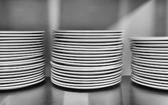 Stack of white washed round plates waiting for serving on a table in a kitchen. Dishware as part of modern comfort.