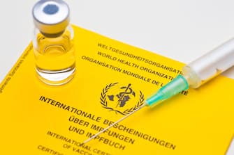 Close-up of yellow vaccination document of the world heatlh organization with syringe an vial